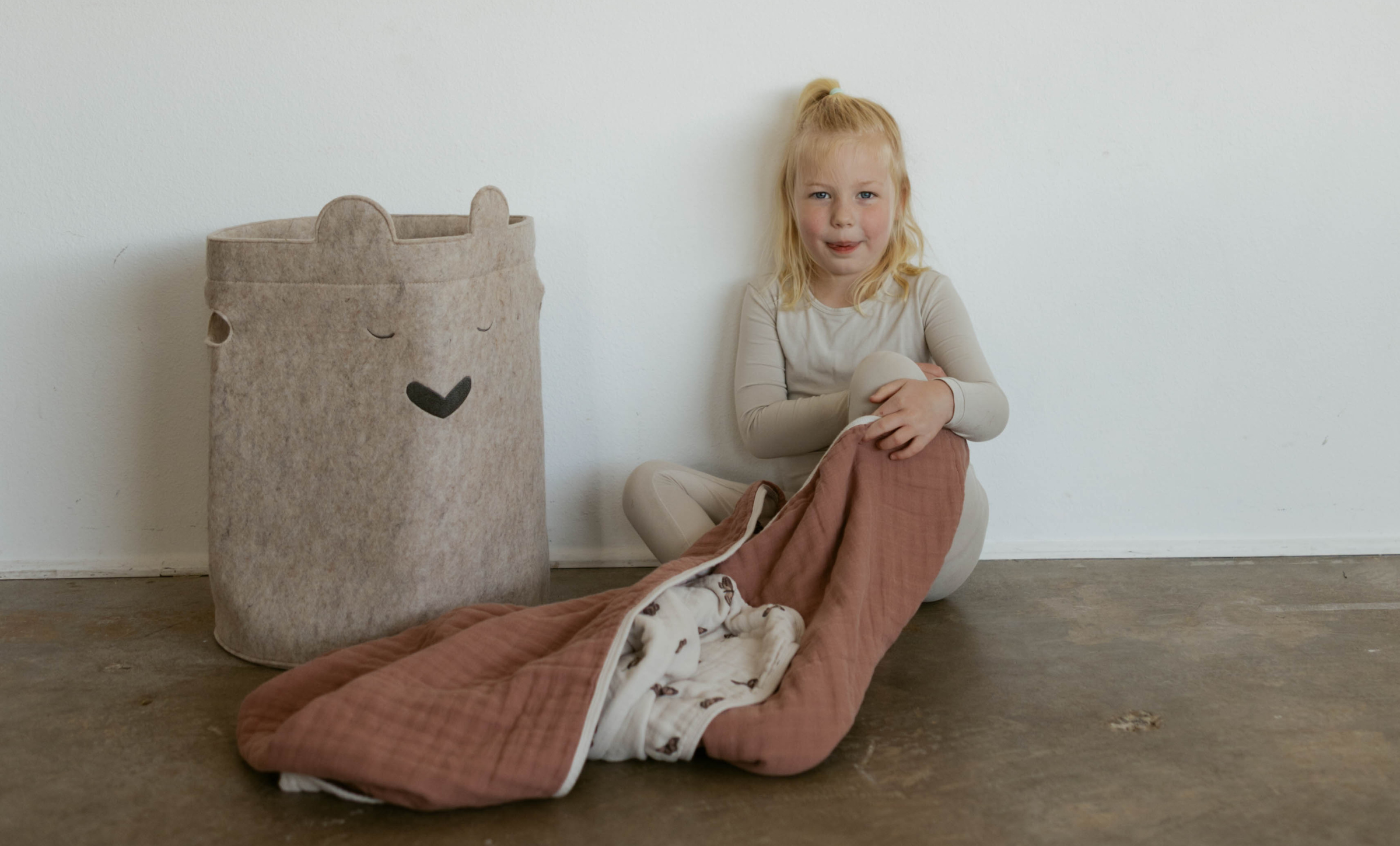 girl sitting on ground with bear hamper