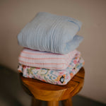 Blossom Swaddle Set stacked on stool. 