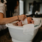 Baby in bathtub with washcloth